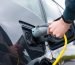 Man plugging in charger into an electric car at charge station